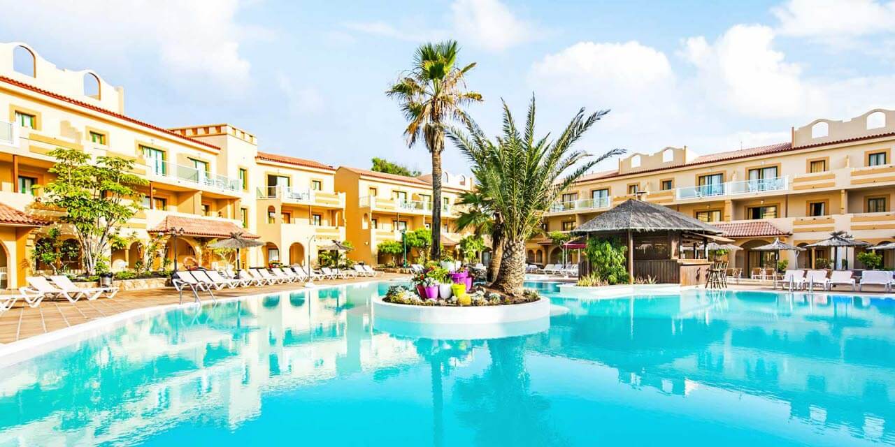 Poolområde med palmer og solsenge ved Elba Lucía Sport Suite Hotel på Fuerteventura